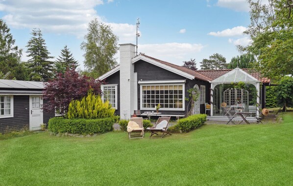 Ett hus med ett stort fönster, en inglasad uteplats och en gräsmatta.