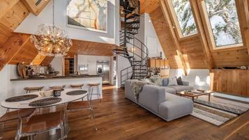 Un vaste loft comprenant une cuisine, un coin repas et un salon, avec des planchers en bois, un escalier en colimaçon et de grandes fenêtres.