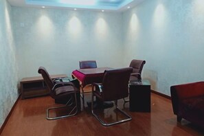 A conference room with a wooden table, four chairs, a laptop, and a small side table. - Guorui Hotel (Jiande)