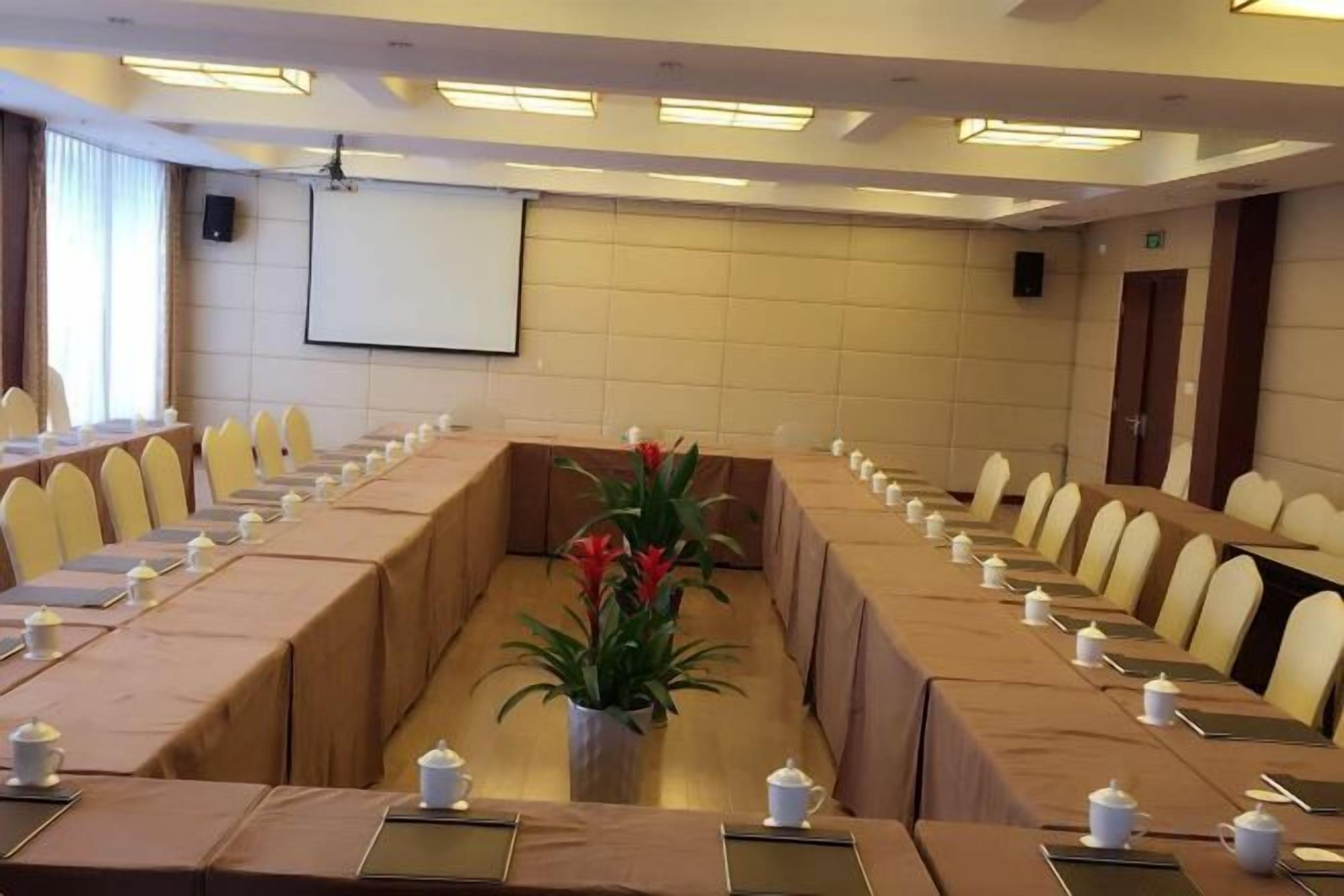 A conference room with a long table, chairs, and a projector screen.