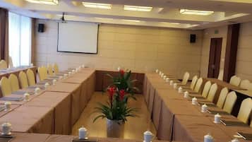 A conference room with a long table, chairs, and a projector screen.