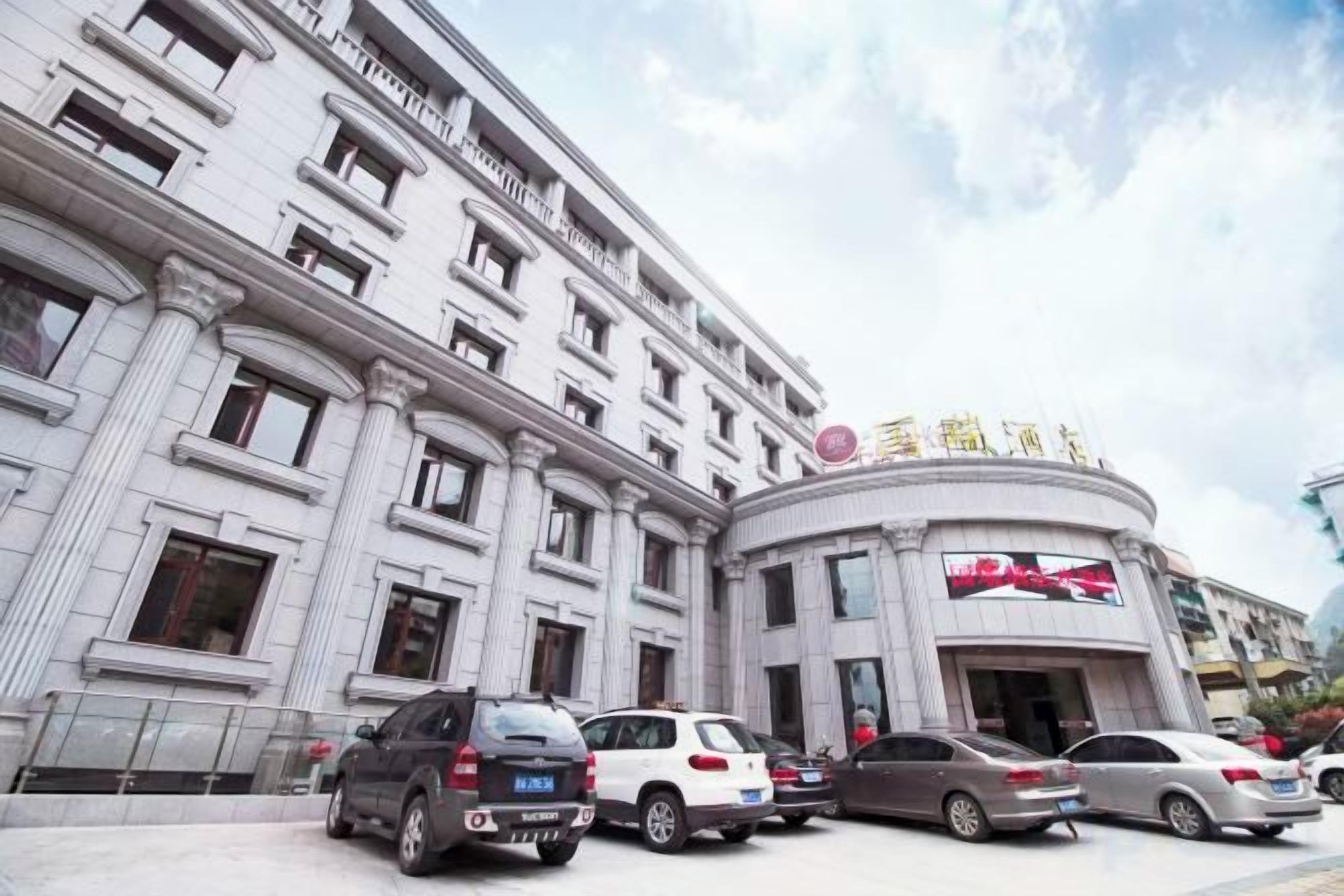 A multi-story hotel with a classical architectural style, featuring a prominent entrance with a curved facade and a large sign above the entrance.