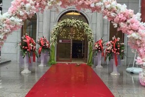 A red carpet leading to an entrance with floral decorations and a grand archway. - Guorui Hotel (Jiande)