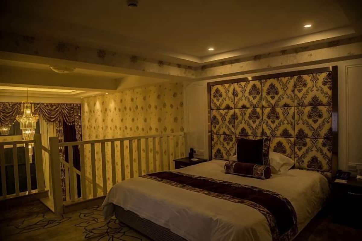 A bedroom with a large bed, a patterned headboard, a nightstand, and a small table.