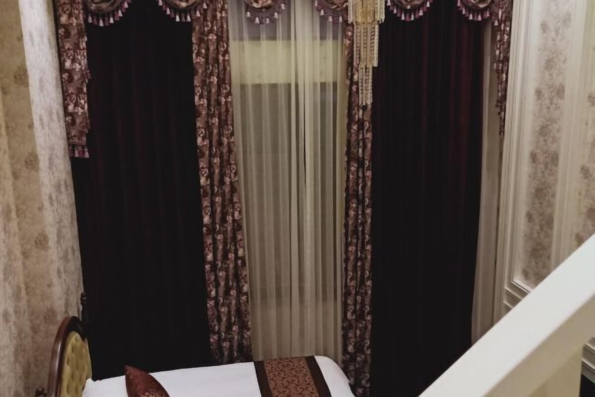 A corner of a room with a bed, a chair, and a staircase.