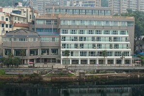 A multi-story building with a modern architectural style, featuring a mix of glass and concrete facades, located near a body of water. - Guorui Hotel (Jiande)