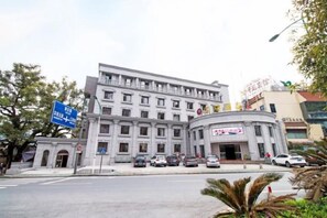 A multi-story building with a central entrance, surrounded by parked cars and a clear sky. - Guorui Hotel (Jiande)