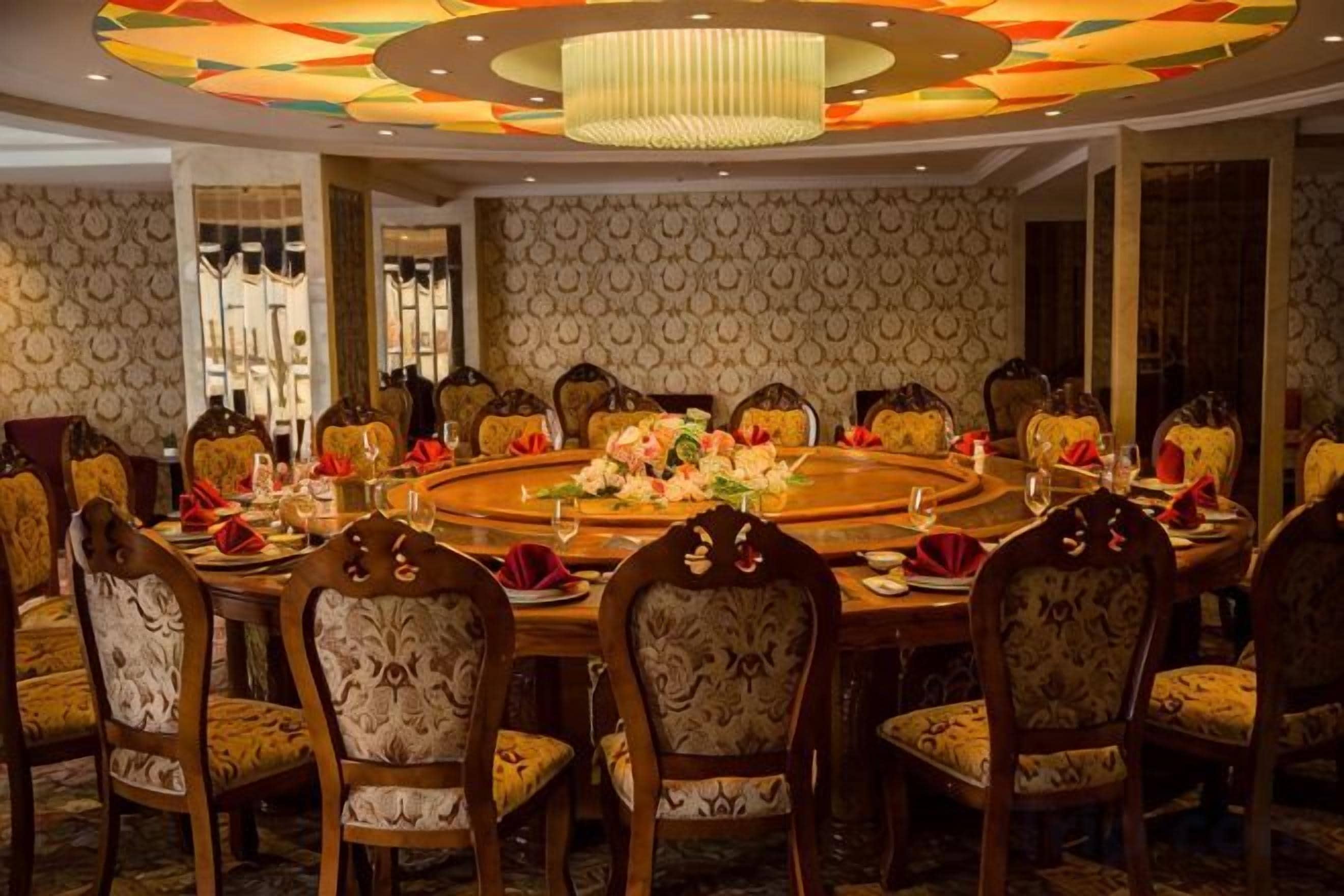 A formal dining room with a round table, multiple chairs, and a chandelier.