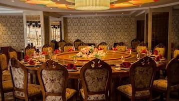 A formal dining room with a round table, multiple chairs, and a chandelier.
