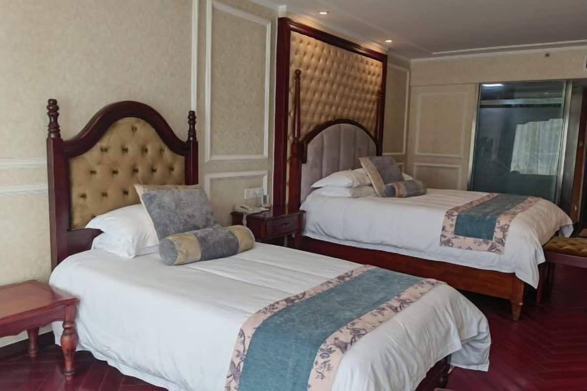 A hotel room with two beds, wooden headboards, and a large mirror.