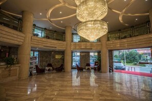 A spacious lobby with a large chandelier, marble flooring, and multiple seating areas. - Guorui Hotel (Jiande)