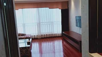 Un salón amplio con un ventanal grande, un sofá, una mesita de centro y un televisor montado en la pared.