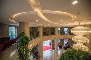 A multi-level hotel lobby with a grand chandelier, a red carpet, and a modern staircase. - Guorui Hotel (Jiande)