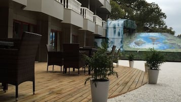 An outdoor seating area with wicker furniture, a wooden deck, and potted plants.