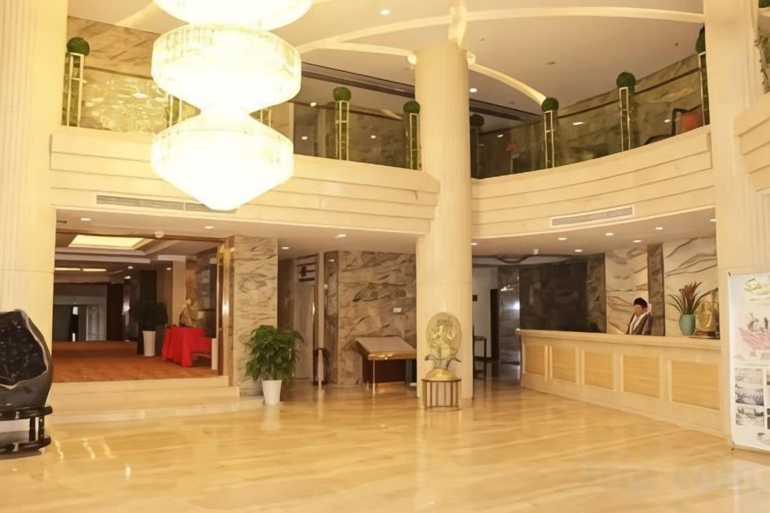 A spacious lobby with a high ceiling, marble flooring, and a reception desk.