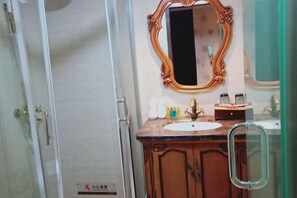 A bathroom with a wooden vanity, a large mirror with an ornate frame, and a glass shower enclosure. - Guorui Hotel (Jiande)