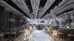 Ein weitläufiger Saal mit einem zentralen Wasserspiel, umrahmt von Tischen und Stühlen, verziert mit floralen Dekorationen und hängenden Laternen.