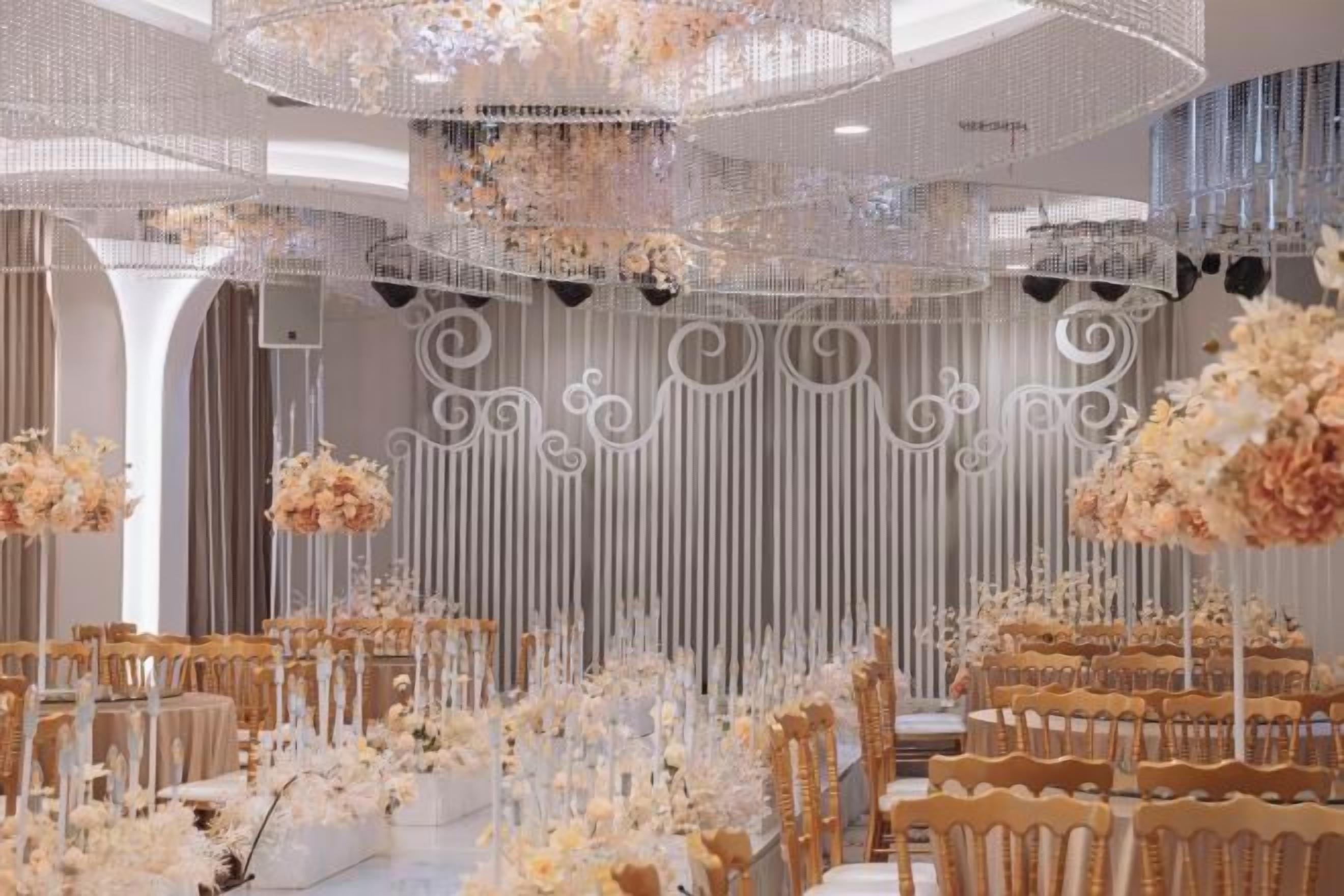 A banquet hall with tiered seating, floral arrangements, and decorative lighting fixtures.