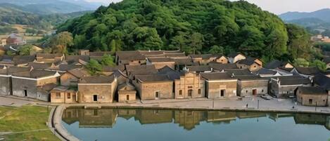 A traditional village with a central pond, surrounded by uniform buildings with sloped roofs.