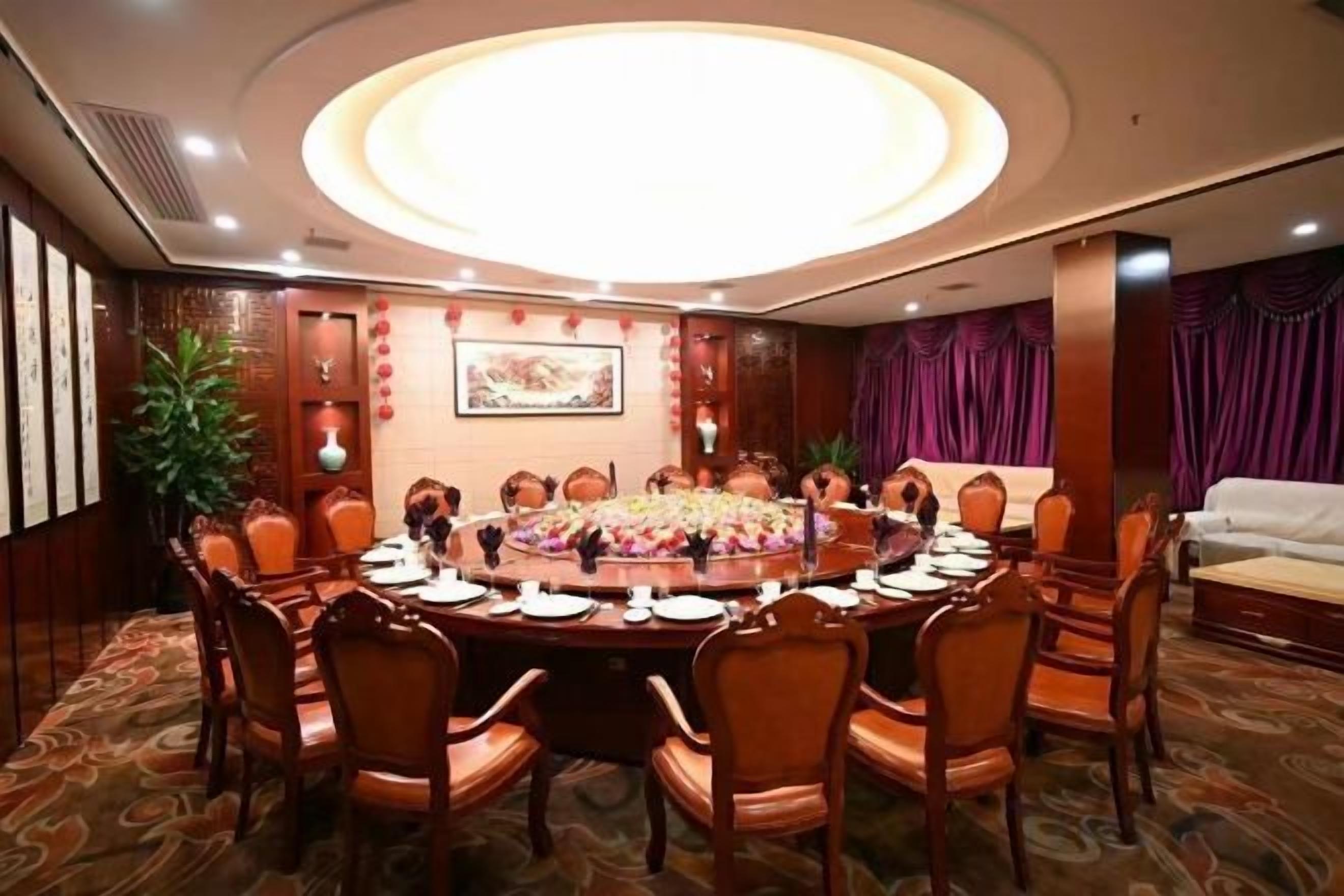 A conference room with a round table, chairs, and a floral centerpiece.