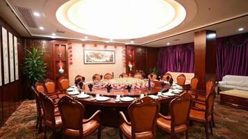 A conference room with a round table, chairs, and a floral centerpiece.