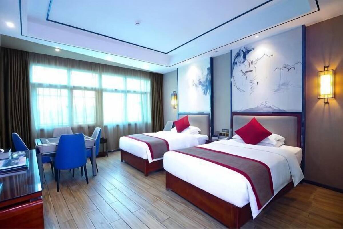 Une chambre d’hôtel avec deux lits, un bureau et une chaise.