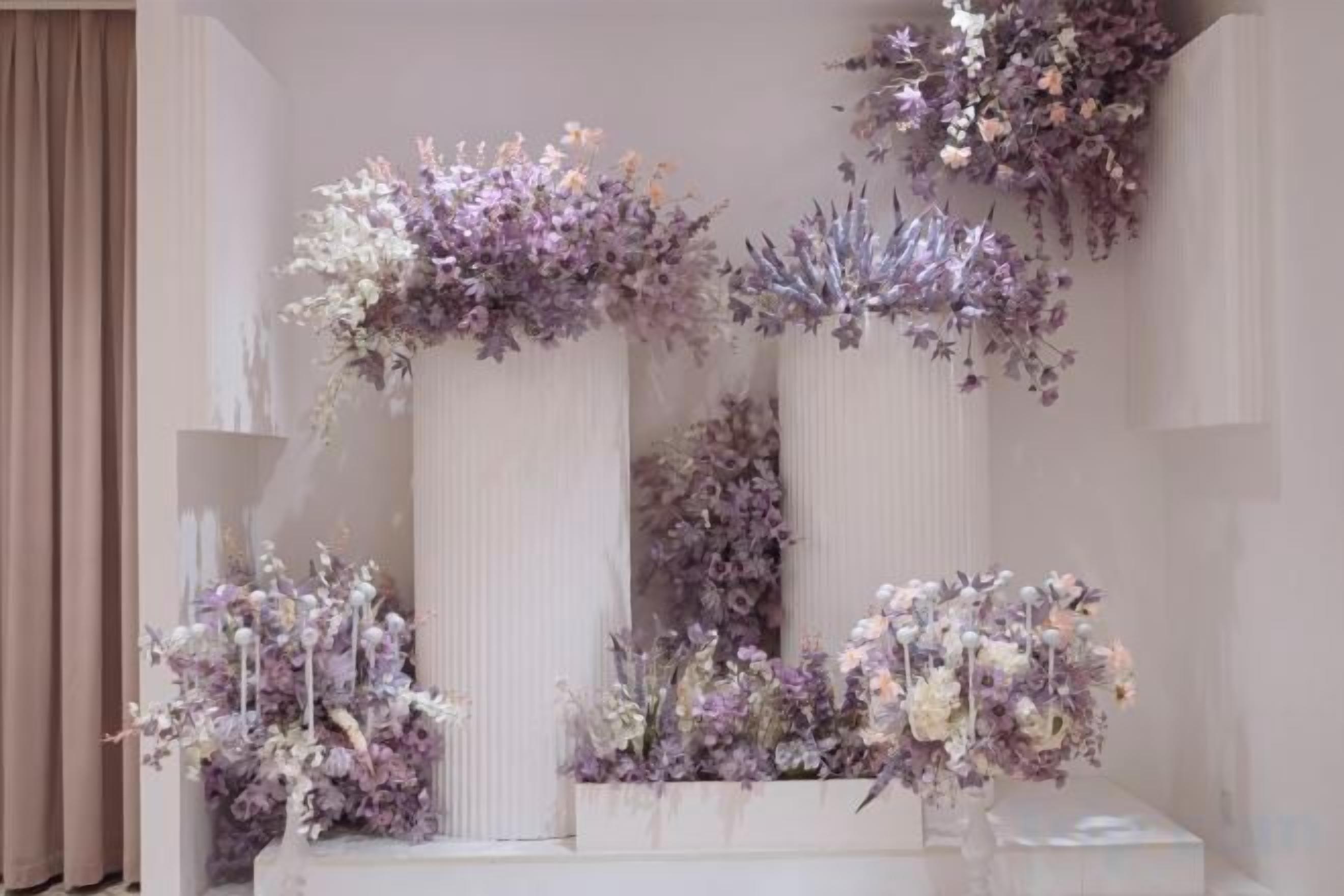 A room with a white reception desk, tall white columns, and floral arrangements.