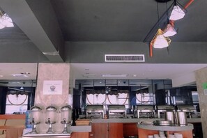 Un buffet avec plusieurs points de service, un système de ventilation et un comptoir muni d’un tableau affichant le menu.