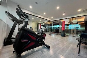 Une salle de sport équipée de matériel d’exercice, d’un tapis de course et d’un rameur.