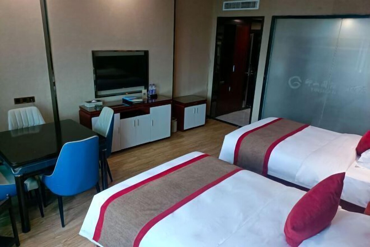 Une chambre d’hôtel avec deux lits, un bureau, une chaise, une télévision et une armoire.