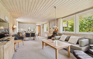 A spacious living area with a wooden ceiling, a sofa set, a dining table, and a kitchen in the background. - Cozy home in Ulfborg with WiFi (Ulfborg)