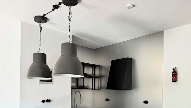 Una cocina moderna con una isla de mármol, luces colgantes y un televisor de pantalla plana.