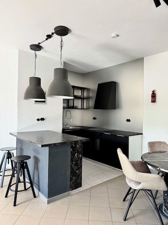 A modern kitchen with a marble island, pendant lights, and a flat-screen TV.. Apartment for 4 people with whirlpool and a large garden