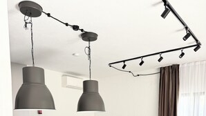 Una cocina moderna con una isla central, taburetes de bar, iluminación colgante y un comedor con sillas.