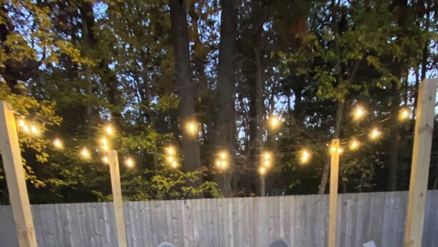 Ein Garten mit Feuerstelle, Gartenmöbeln und Lichterketten.