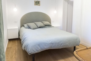 A single bed with a curved headboard, two bedside tables, and a wooden floor.