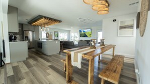 A modern kitchen with a central island, wooden flooring, and a dining area with a bench. - beautiful country house (Clermont)