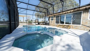 A swimming pool with a hot tub, surrounded by a glass enclosure, and a stone building with large windows. - beautiful country house (Clermont)