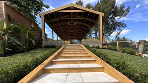 A wooden staircase leading to a covered area with a stone wall and greenery. - beautiful country house (Clermont)