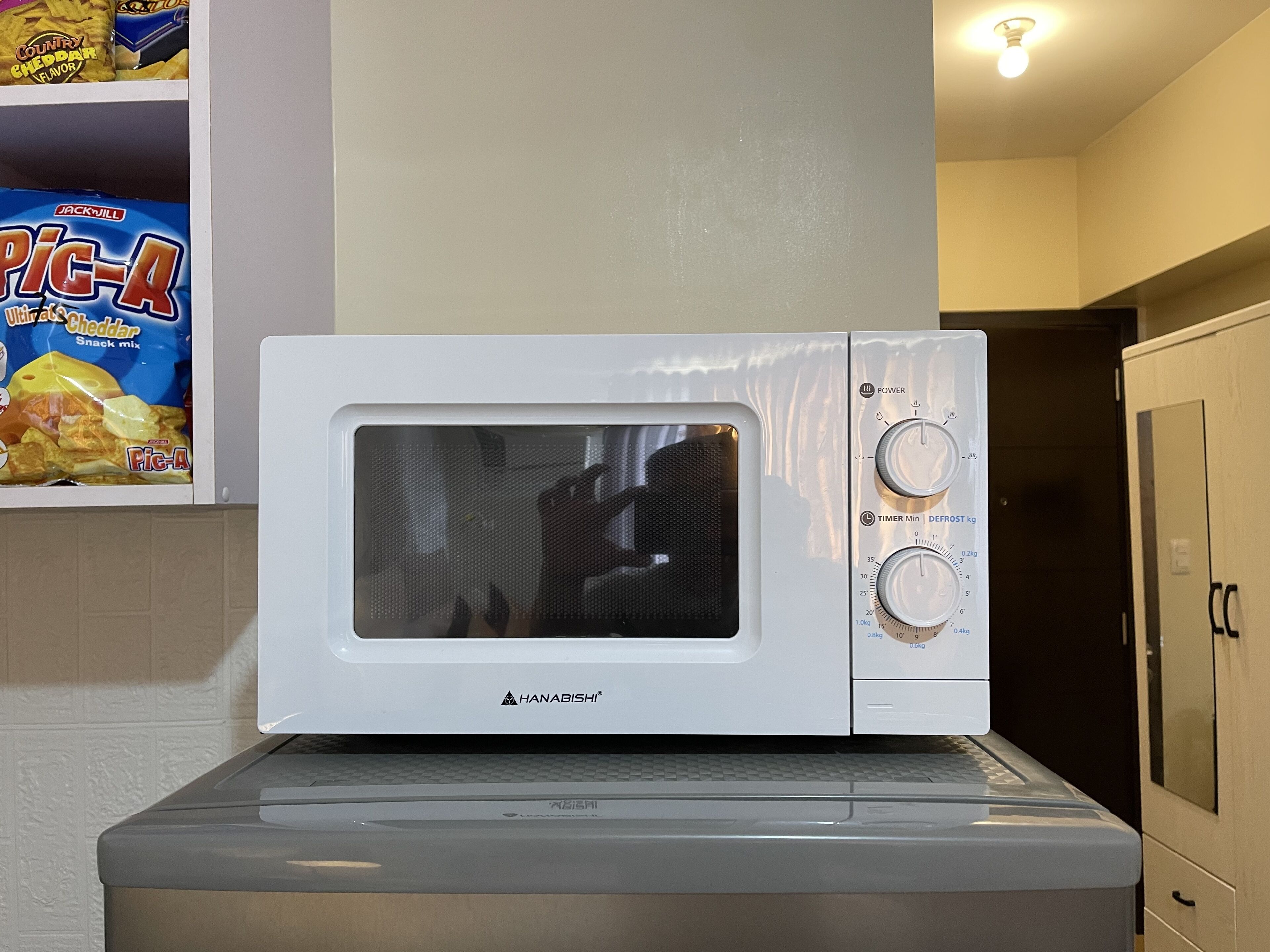 A white microwave oven with a digital display and control knobs, placed on a kitchen counter.