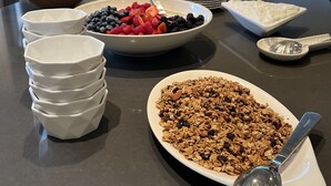 Un buffet de petit-déjeuner proposant une variété d’aliments, avec une cuisine moderne en arrière-plan.