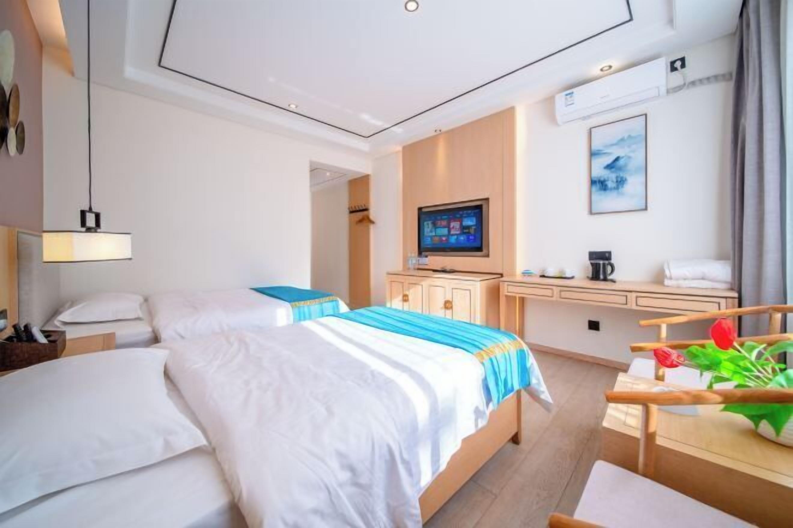 Habitación de hotel con dos camas, un escritorio, un televisor y una ventana con vistas.