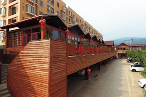 A modern building with a wooden facade and balconies. - Xinjia Yuquan Hot Spring Hotel (Mile)
