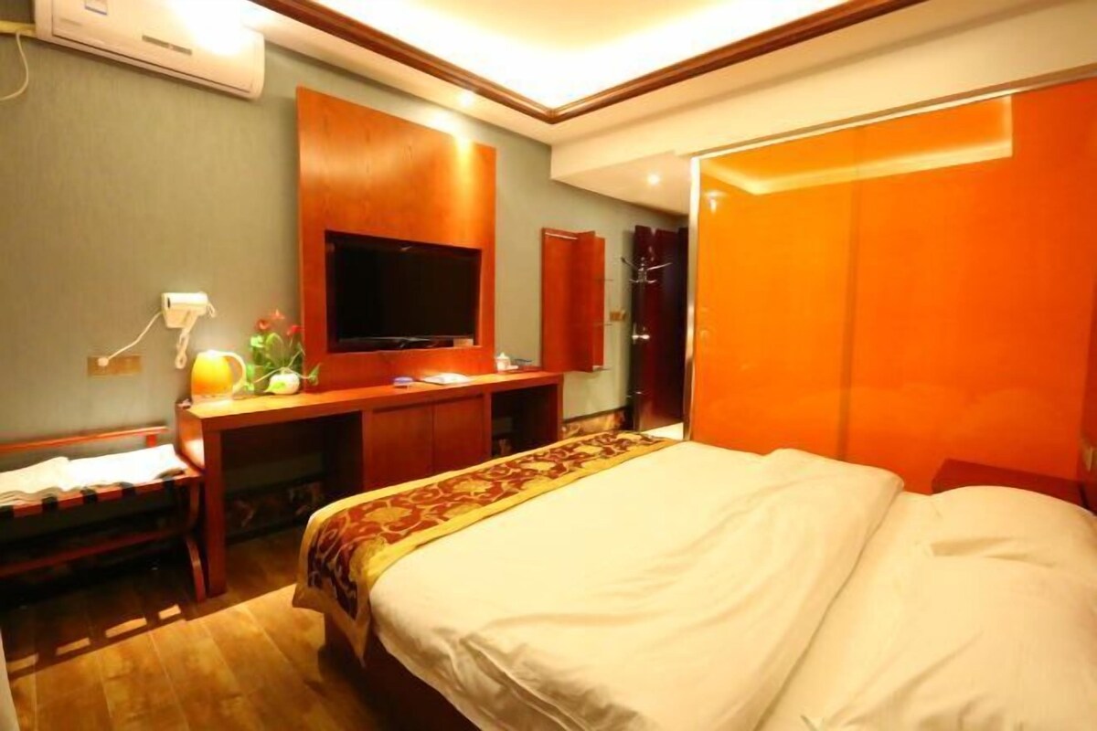 A hotel room with a bed, a desk, a television, and a wardrobe.
