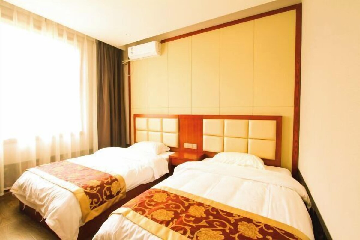 A hotel room with two beds, a wooden headboard, and a window with curtains.