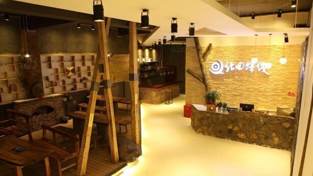 Interior acogedor de un restaurante con mobiliario de madera, una barra de piedra y un ambiente cálido.