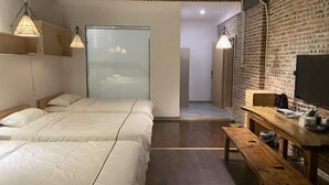 Una habitación de hotel moderna con dos camas, un banco de madera, un televisor y una pared de ladrillo.