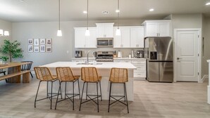 A modern kitchen with white cabinets, stainless steel appliances, and a central island with bar stools.
