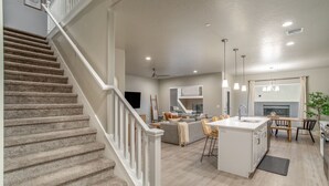 A spacious living area with a central island, a staircase, and a kitchen area with a dining table.