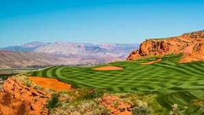 A golf course with a clear view of the surrounding red rock formations and distant mountains.